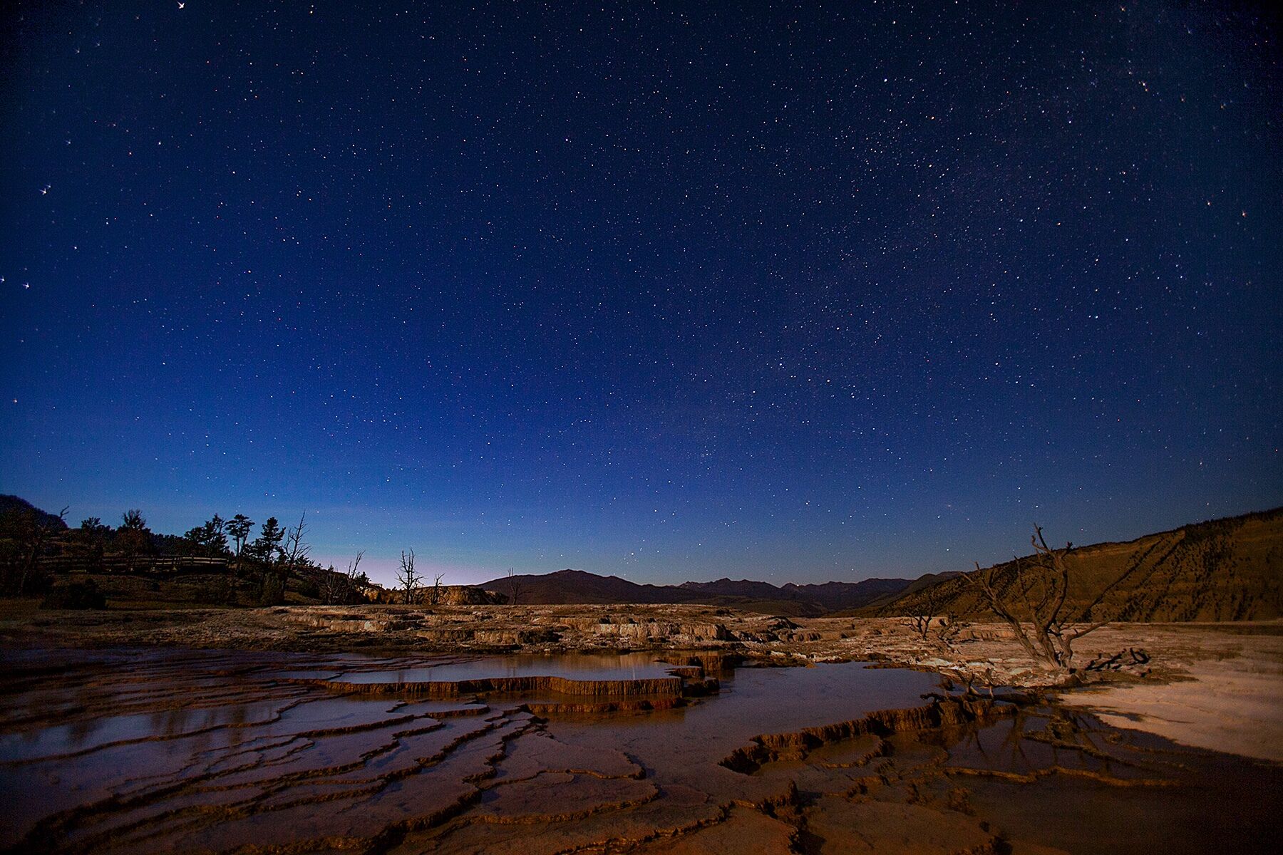 Mammoth hot springs under a starry night sky in Yellowstone National Park, Wyoming