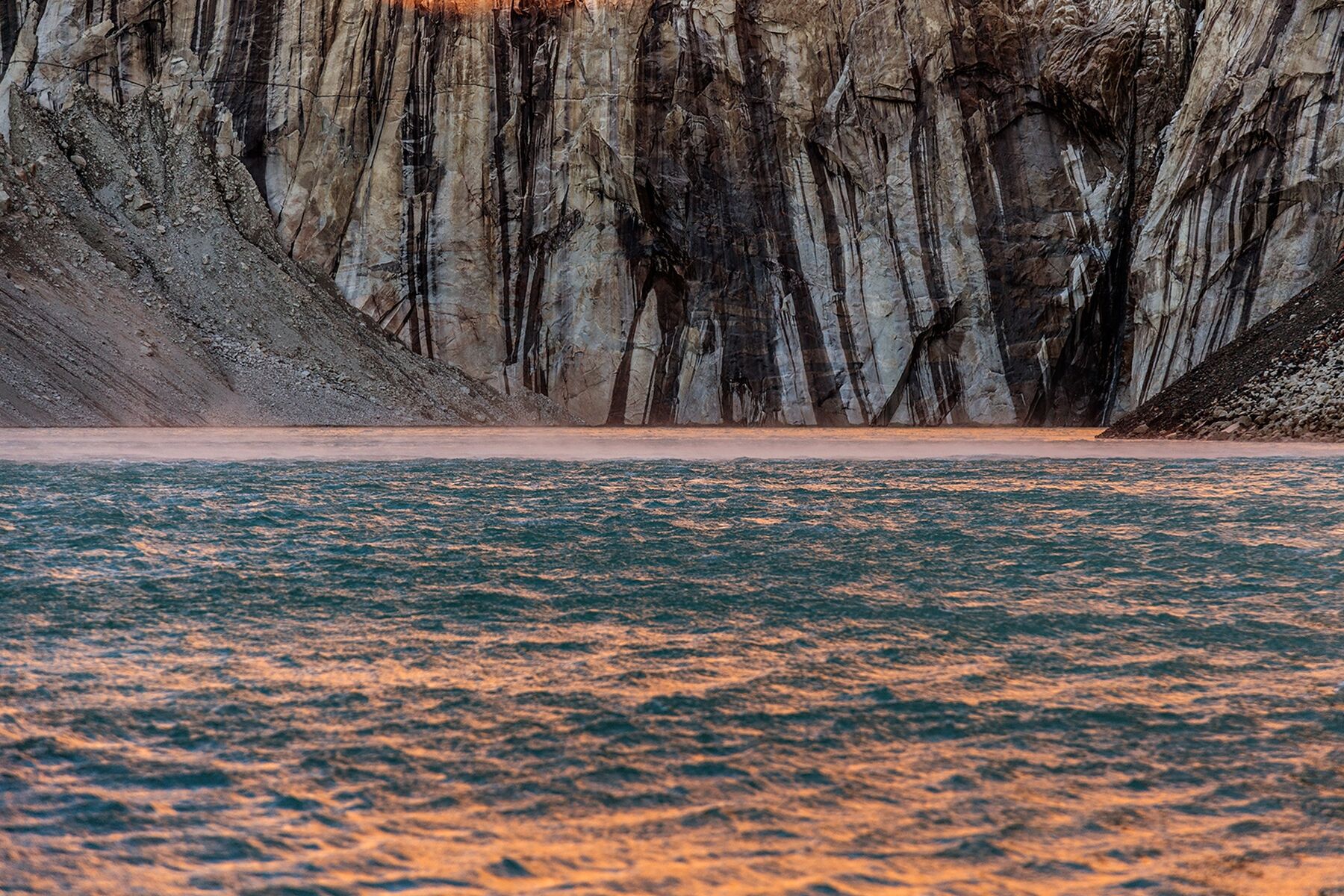 Close-up shot of water with pink sunlight reflected at the base of Torres Del Paine