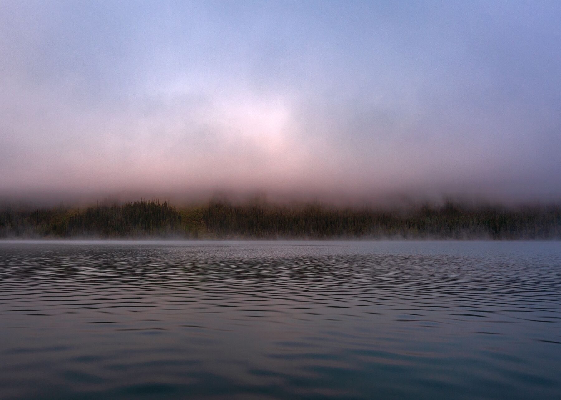 Fog hovers of the calm waters of Maligne Lake in Jasper National Park, Alberta, Canada