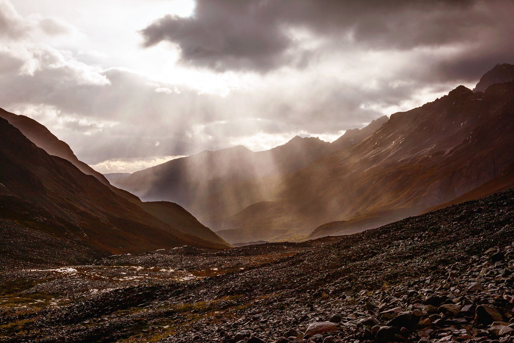 Sun breaks through a cloudy sky over Paso John Gardner in Torres Del Paine National Park, Chilean Patagonia