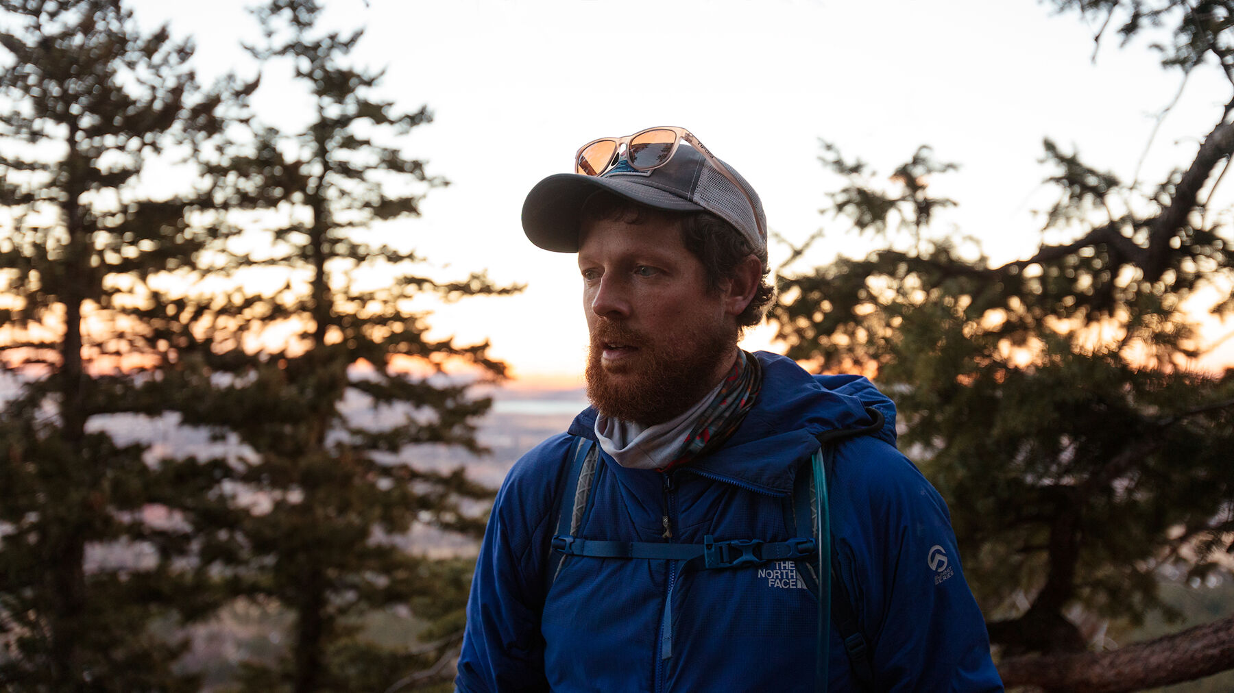 Dan takes a break on a hike in the Flatirons in Boulder, Colorado, with light from the setting sun breaking through the trees behind him.