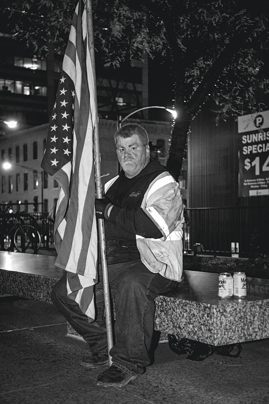 A man sitting with a large American Flag at the demonstration protesting the election of Donald Trump in Chicago