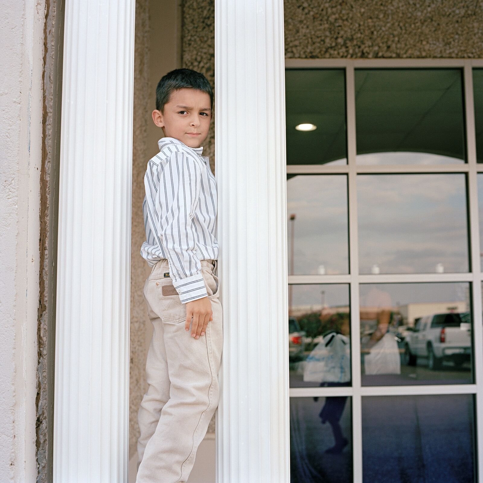 Richie standing between two white pillars in front of a building