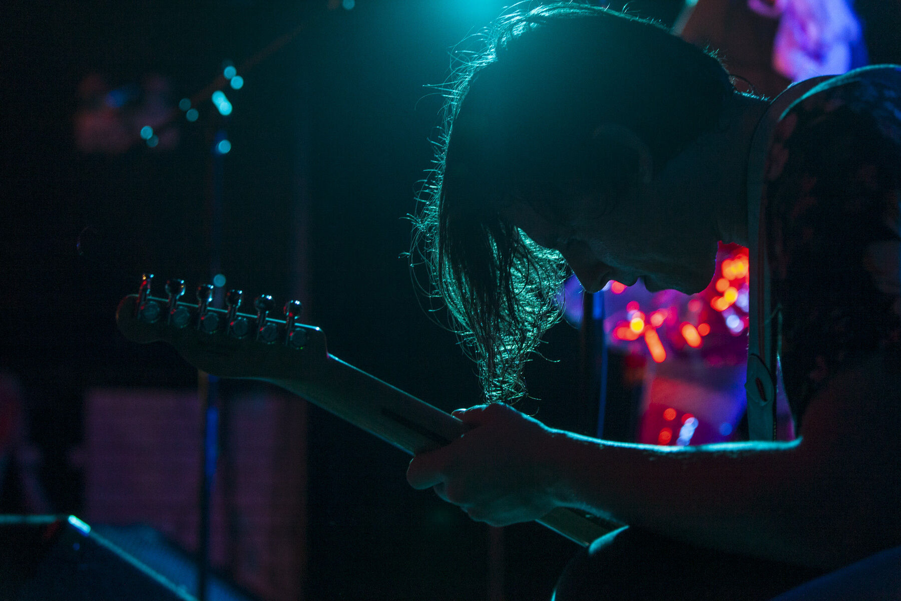 Guitarist silhouetted by lights performing on stage