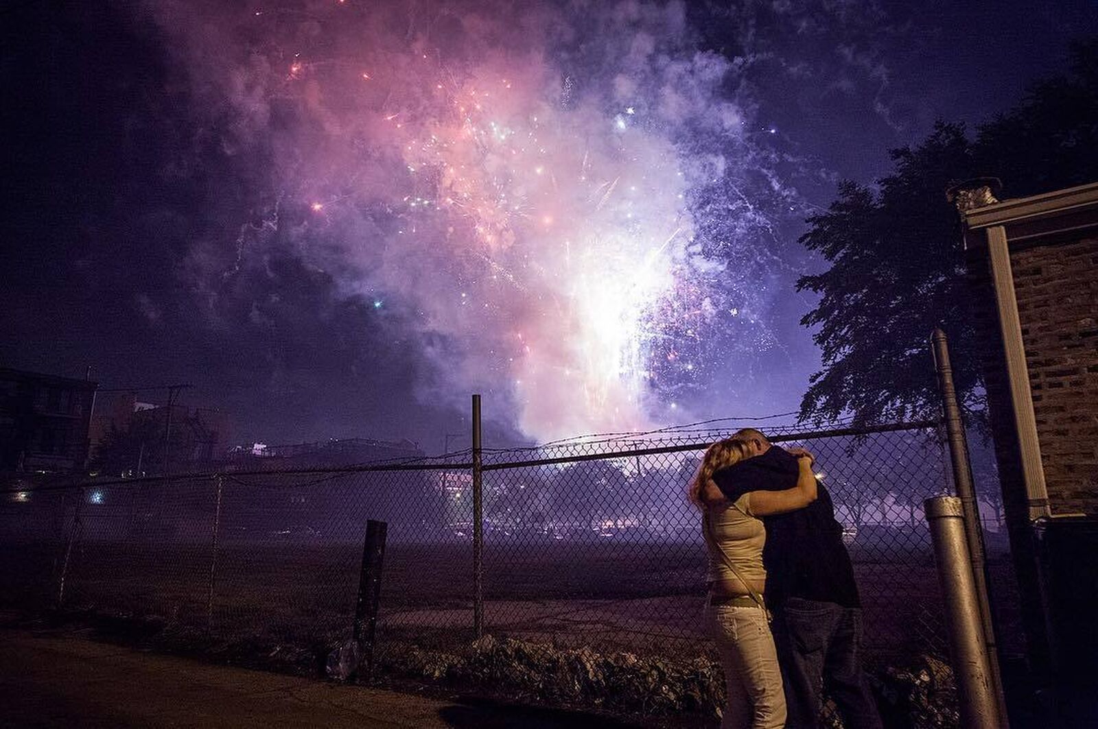 A couple embraces in front of fireworks in an alley in Chicago on July 4th