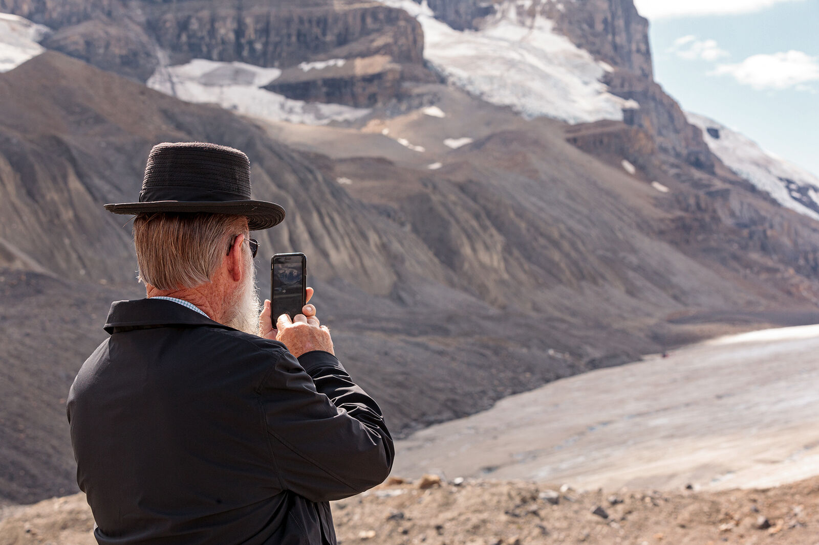 Man taking a photo of the Athabasca Glacier on his cellphone in Alberta, Canada