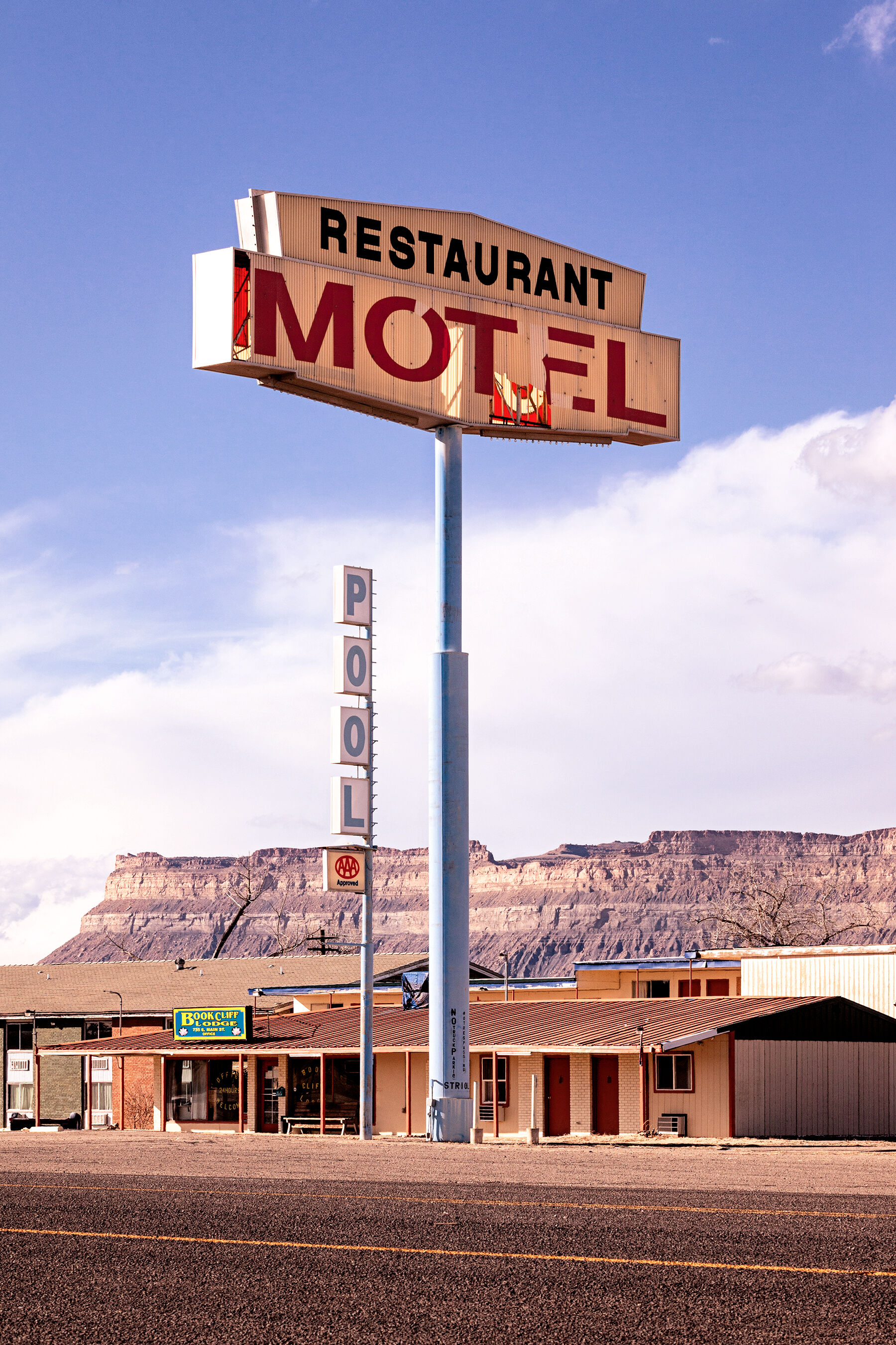 Very tall old motel sign in Green River, Utah with sandstone cliffs in the background